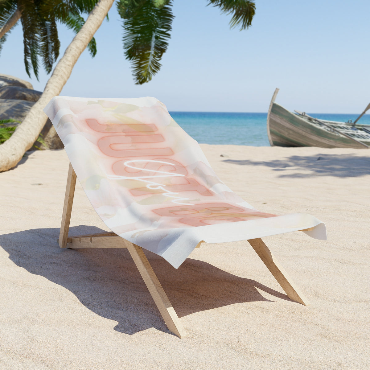 Beach chair with a towel featuring abstract designs 'Just be You' on a sandy beach with palm trees and ocean in the background.