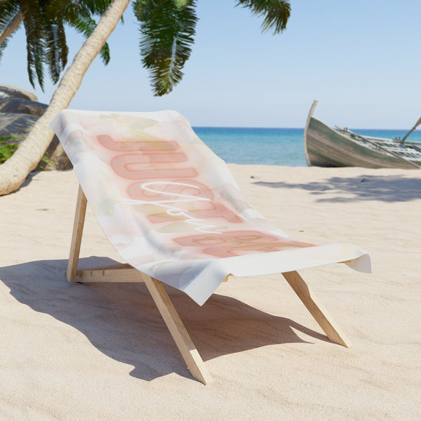 Beach chair with a towel featuring abstract designs 'Just be You' on a sandy beach with palm trees and ocean in the background.