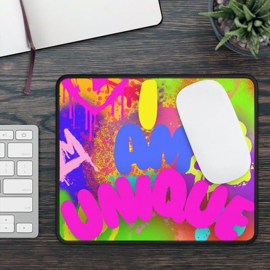 Colorful neoprene gaming mouse pad with black stitched edges for a premium and durable finish with 'I am unique' text on a desk with a keyboard and plant.